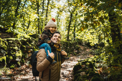 Father carrying child on shoulders in nature